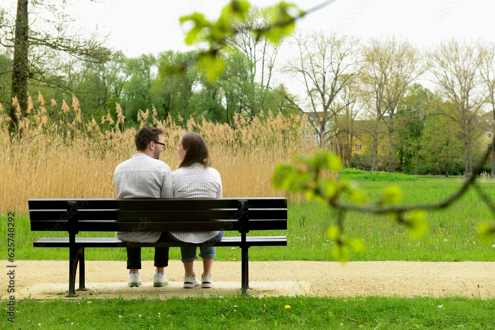 Beautiful loving couple sitting on bench in park