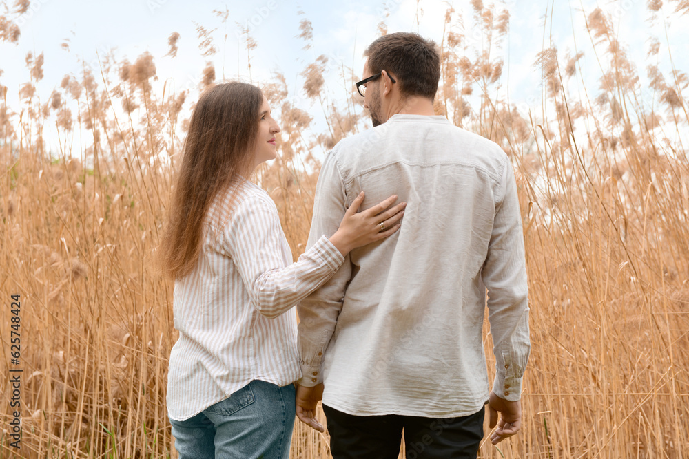 Beautiful happy loving couple hugging in field on spring day