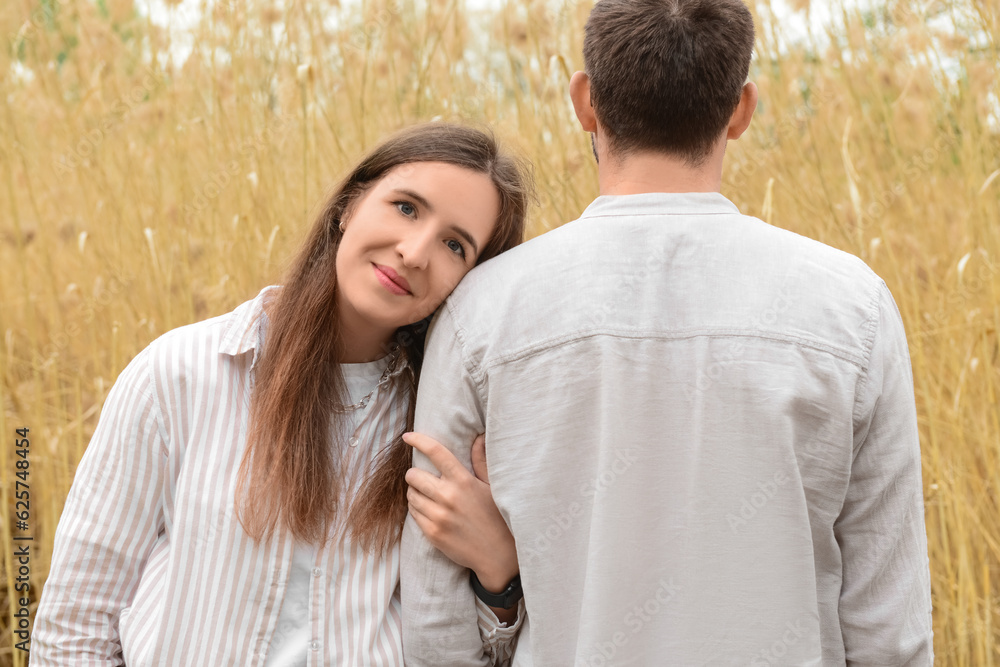 Beautiful happy loving couple hugging in field on spring day