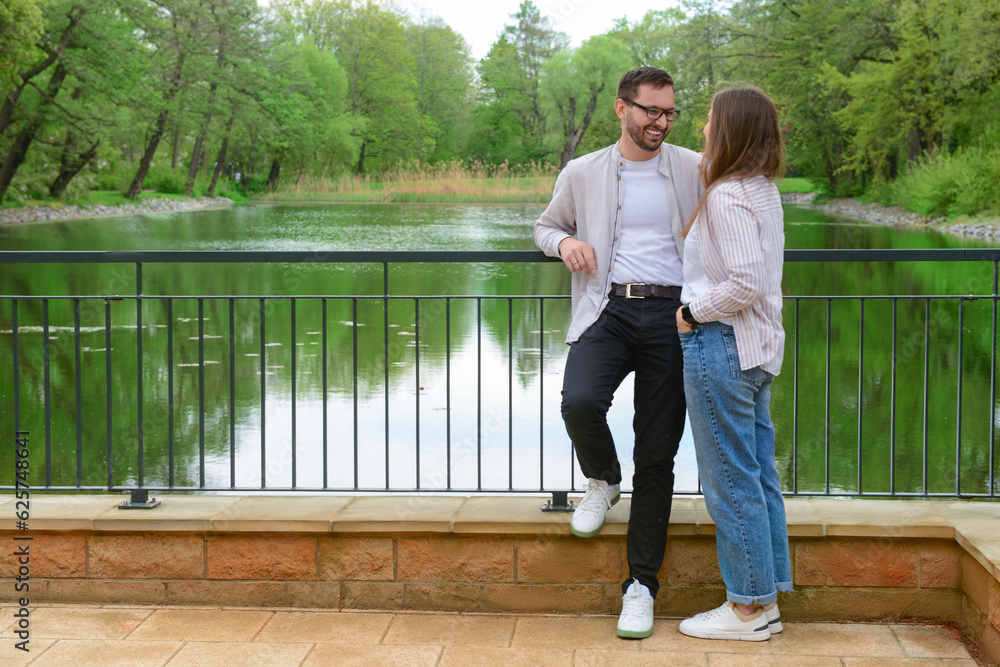 Beautiful loving happy couple speaking on bridge in park