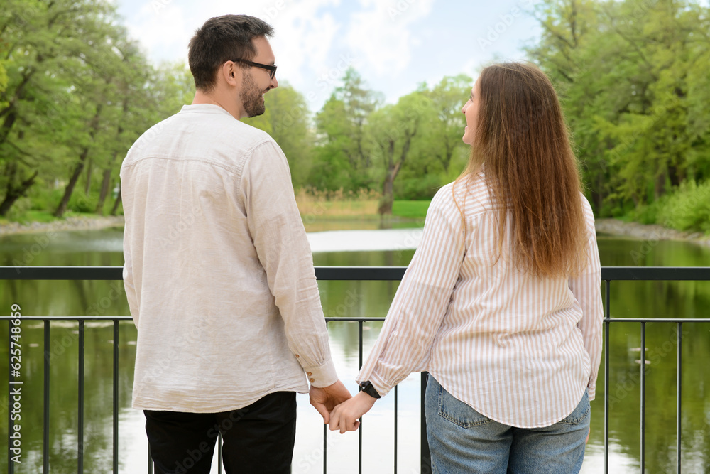 Beautiful loving happy couple holding hands on bridge in park