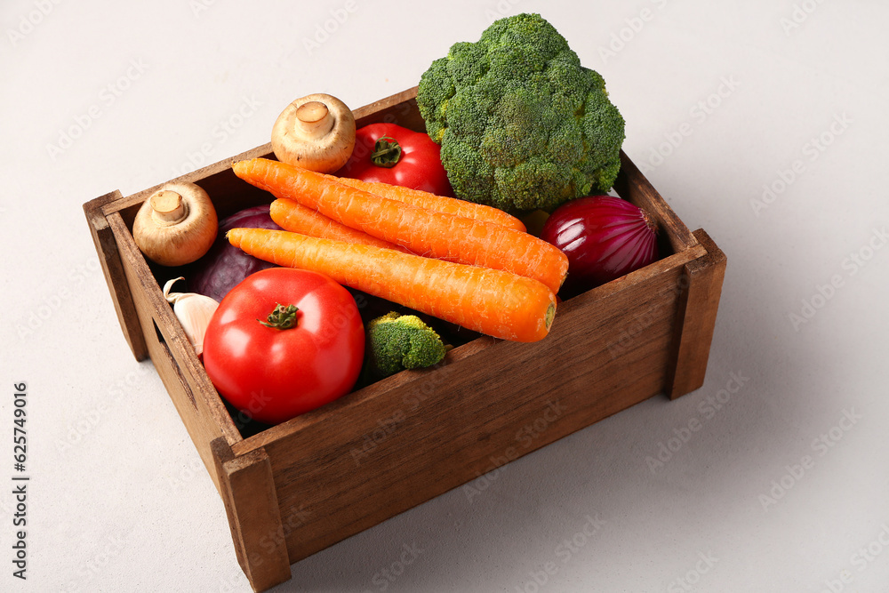 Wooden box with different fresh vegetables on white background