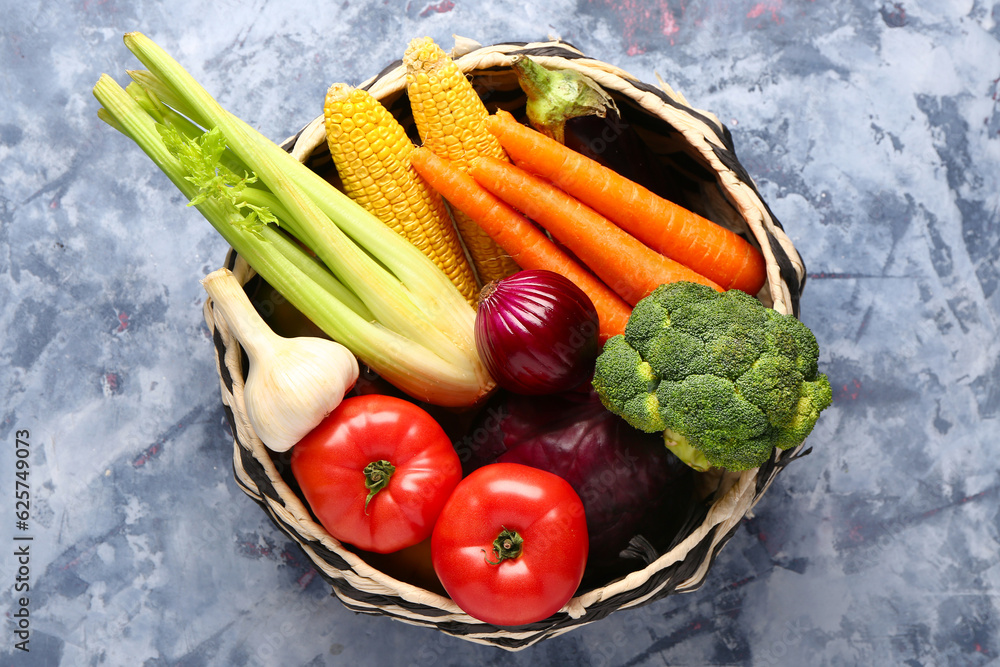 Wicker bowl with different fresh vegetables on blue background