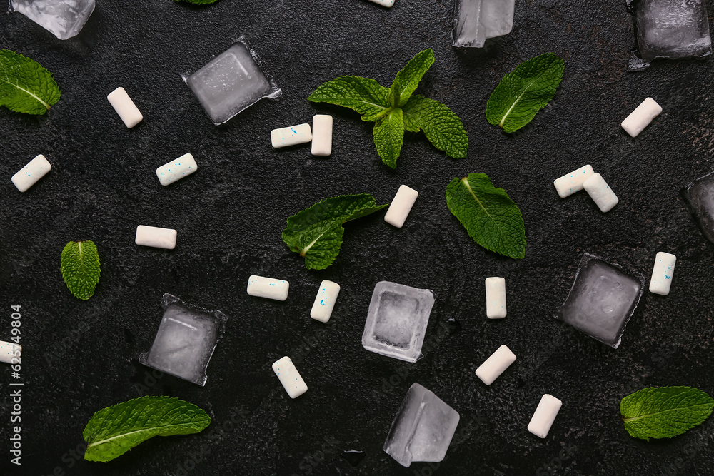 Fresh chewing gums with mint and ice cubes on black background