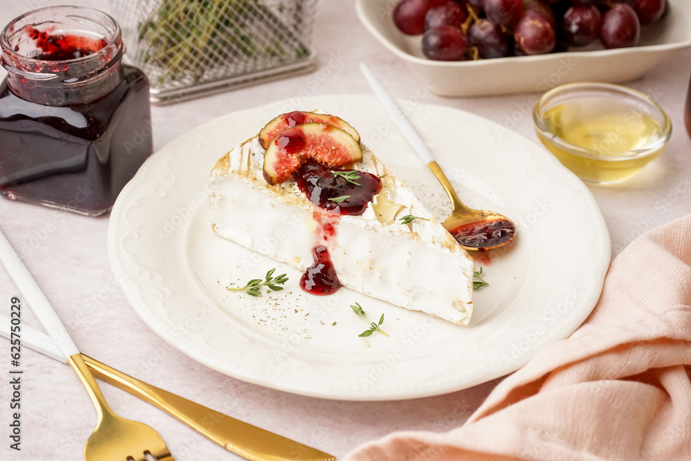 Plate with tasty baked Camembert cheese on light background