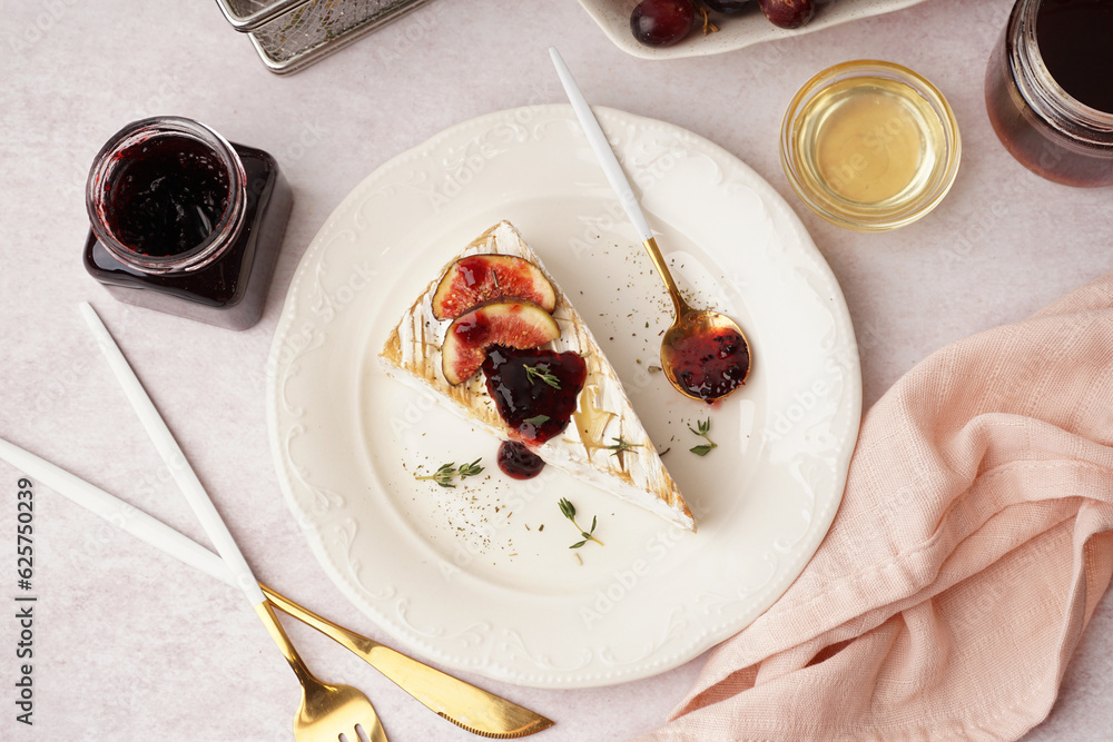 Plate with tasty baked Camembert cheese on light background