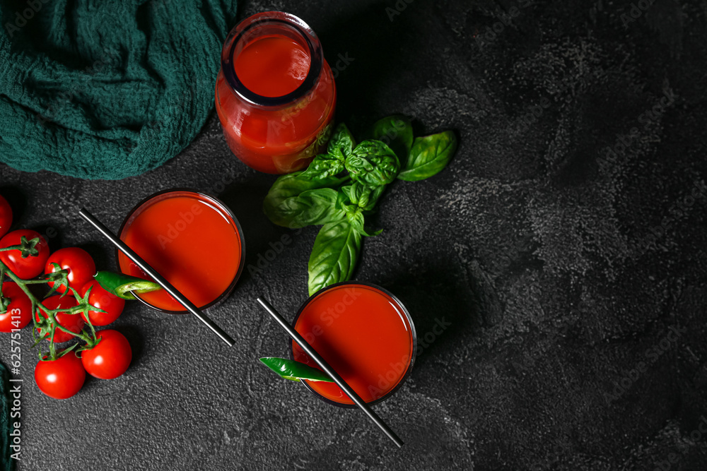 Glasses and bottle of tasty tomato juice on black background