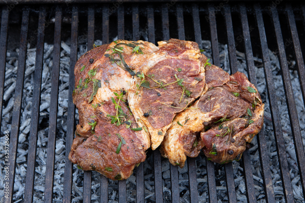 Beef steaks cooking on the charcoal grill with chili pepper, tomatoes, garlic and mushrooms for bbq 