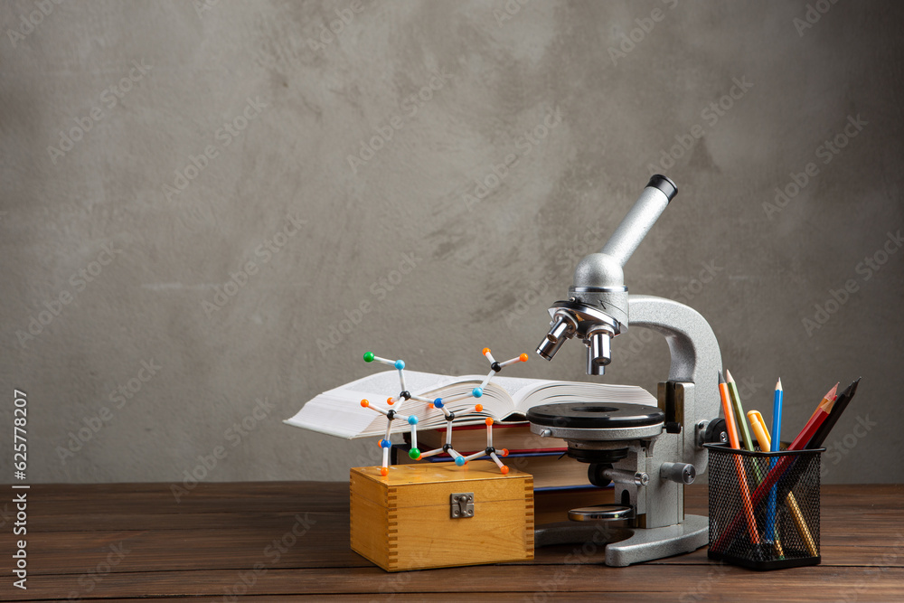 Back to school - books and microscope on the wooden desk in the auditorium, Education concept