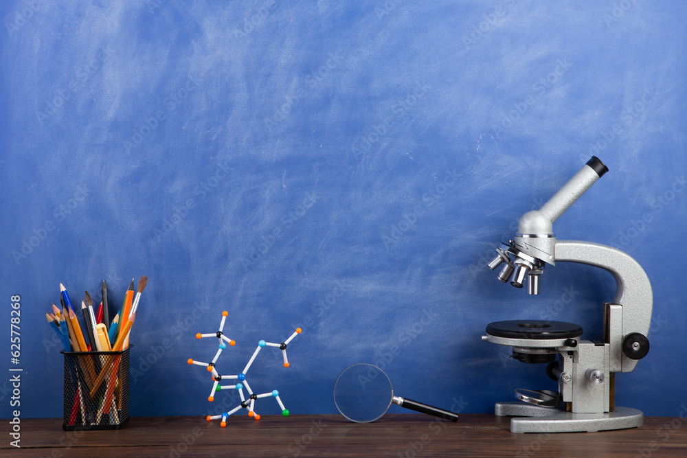 Back to school - microscope on the desk, Education concept. Blackboard background