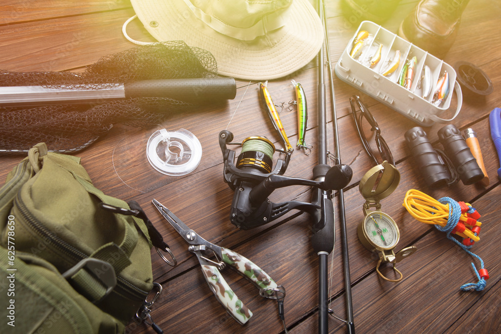 Fishing rod, tackles and other stuff for recreation activity on the wooden desk. Fishing season conc