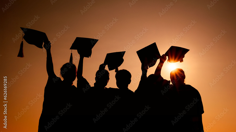 silhouette of Celebration happy students throwing graduation caps in the air at sunrise