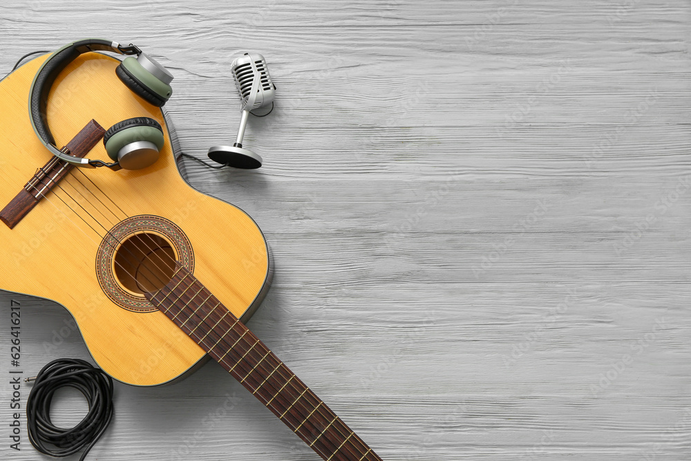 Guitar, headphones and microphone on wooden background