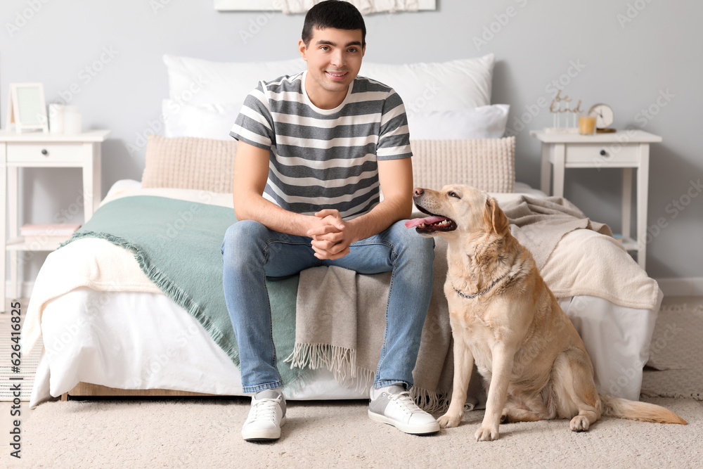 Young man with Labrador dog in bedroom