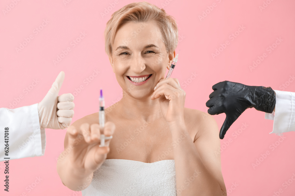 Mature woman with filler injections and gesturing beauticians hands on pink background, closeup