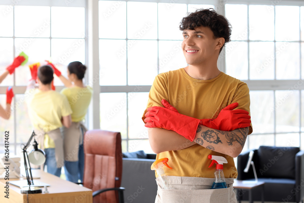 Male janitor with rubber gloves in office