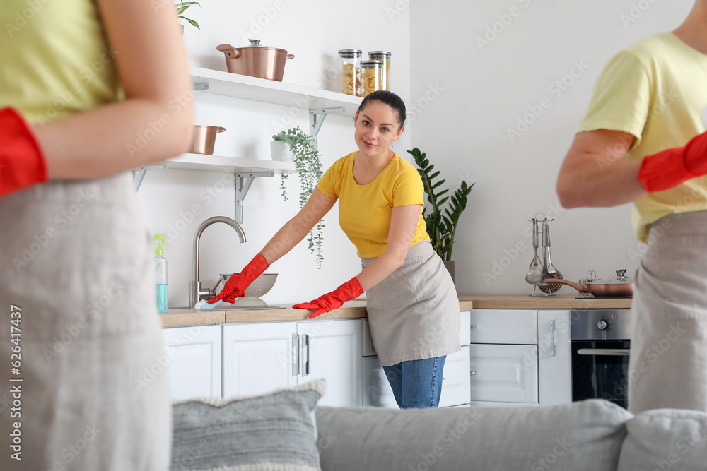 Female janitor cleaning counter in kitchen