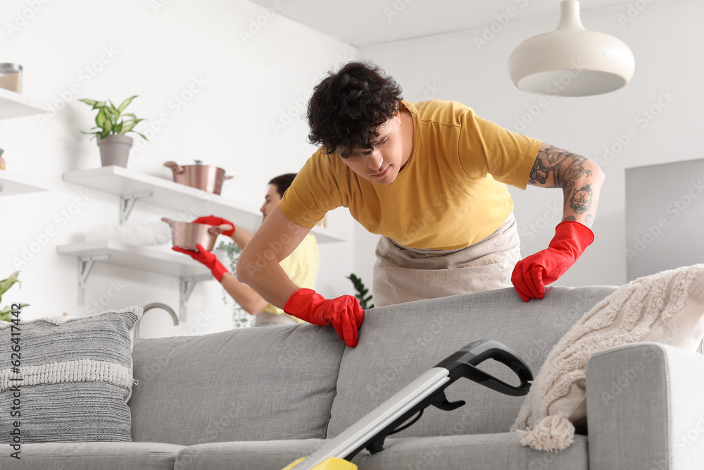 Male janitor fixing sofa in kitchen