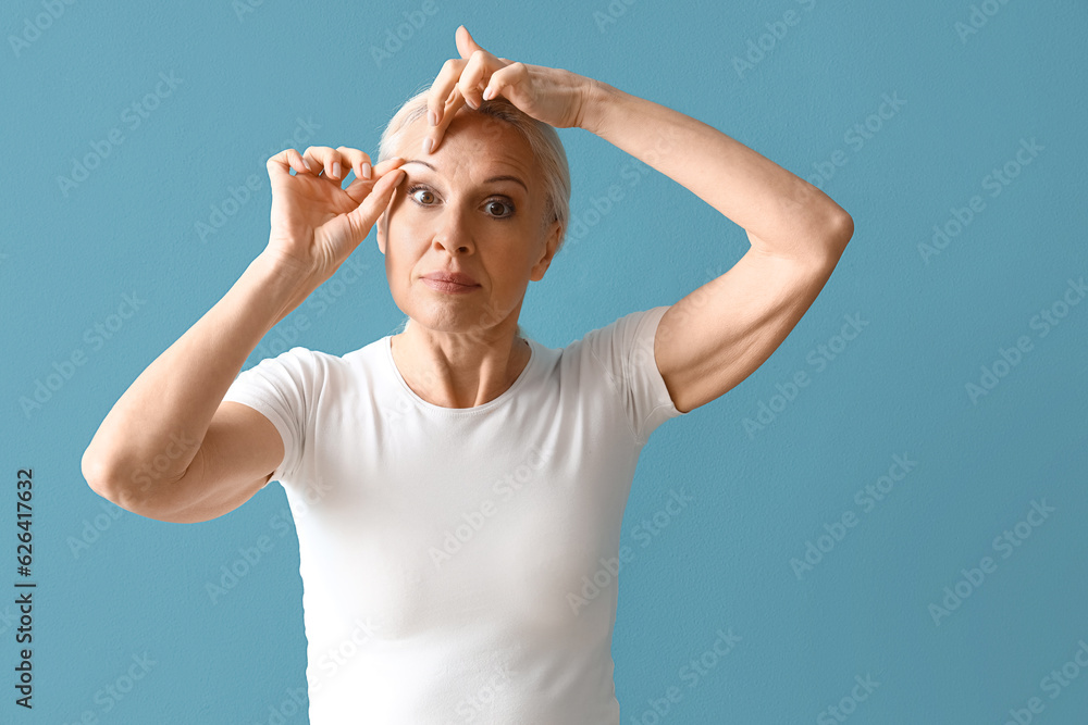 Mature woman doing face building exercise on blue background