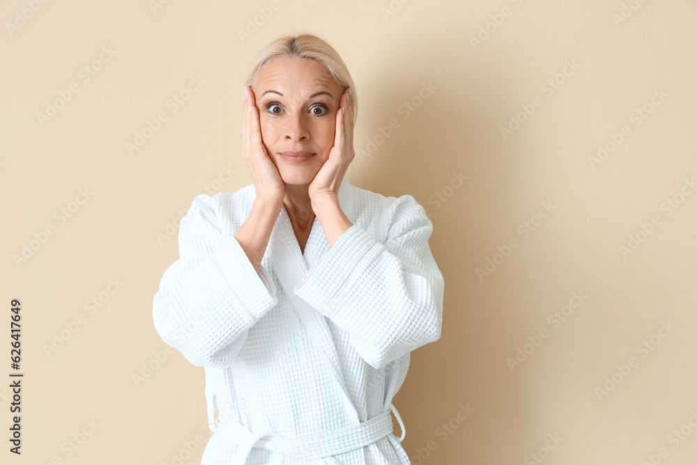 Mature woman doing face building exercise on beige background