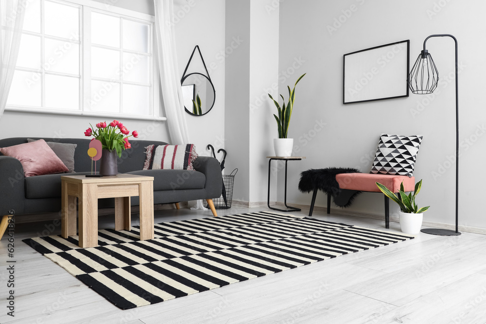 Interior of light living room with sofa, bench, coffee table and tulip flowers