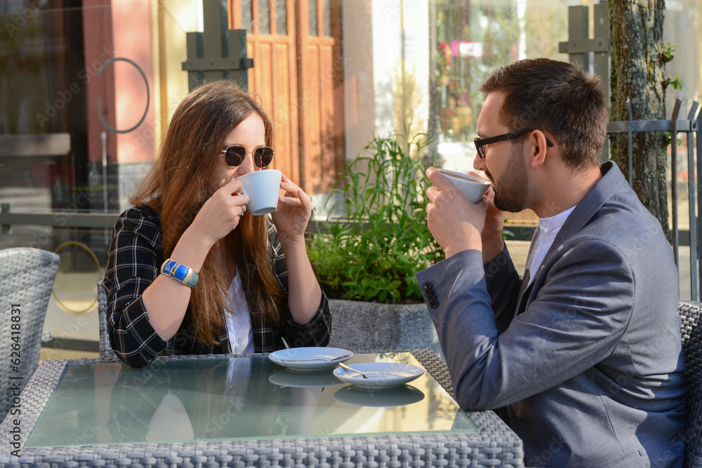 Beautiful happy loving couple sitting in restaurant and drinking coffee on sunny spring day