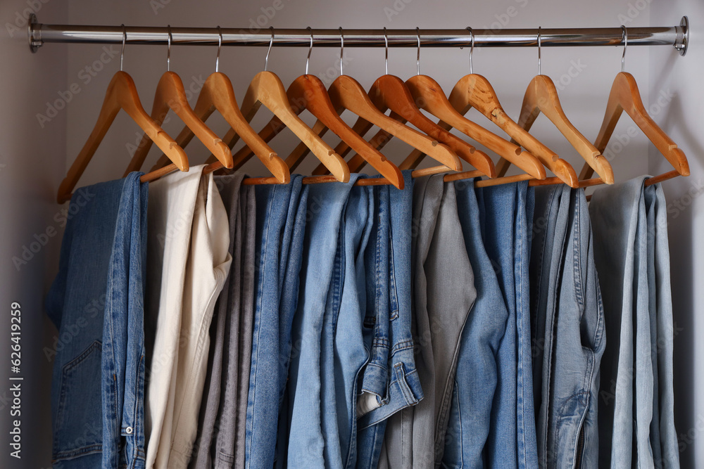 Stylish jeans hanging on rack in boutique, closeup