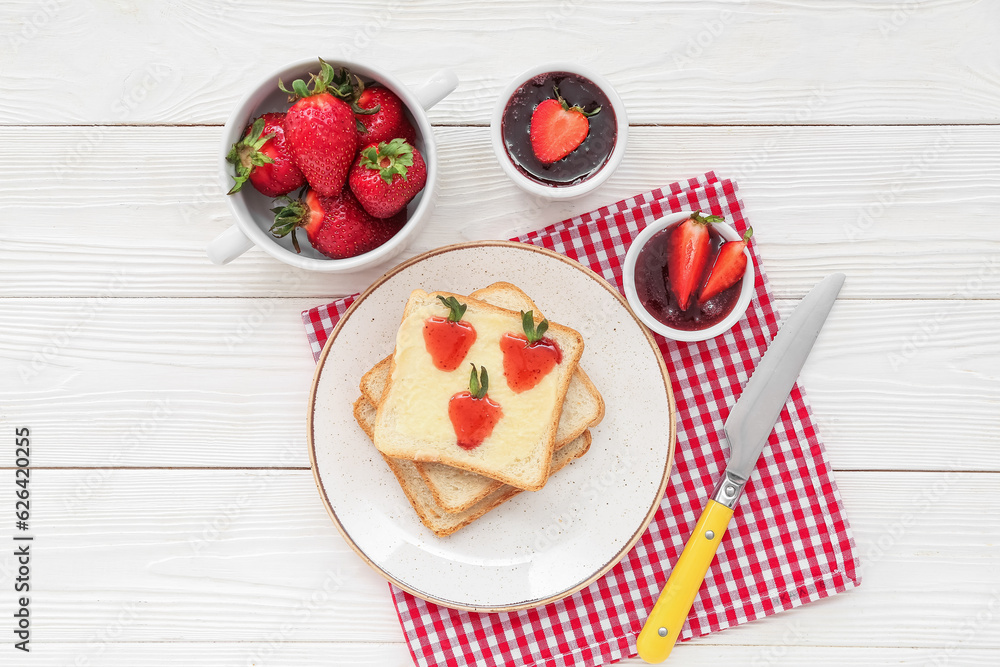 Plate of tasty toasts with sweet strawberry jam and fresh berries on white wooden background