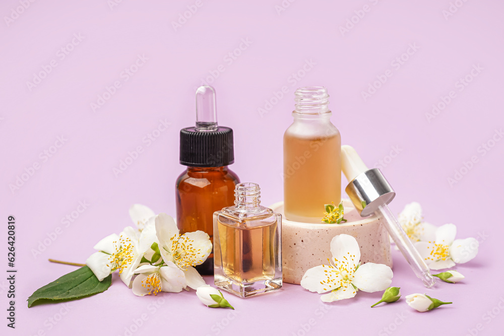 Composition with bottles of essential oil and beautiful jasmine flowers on lilac background