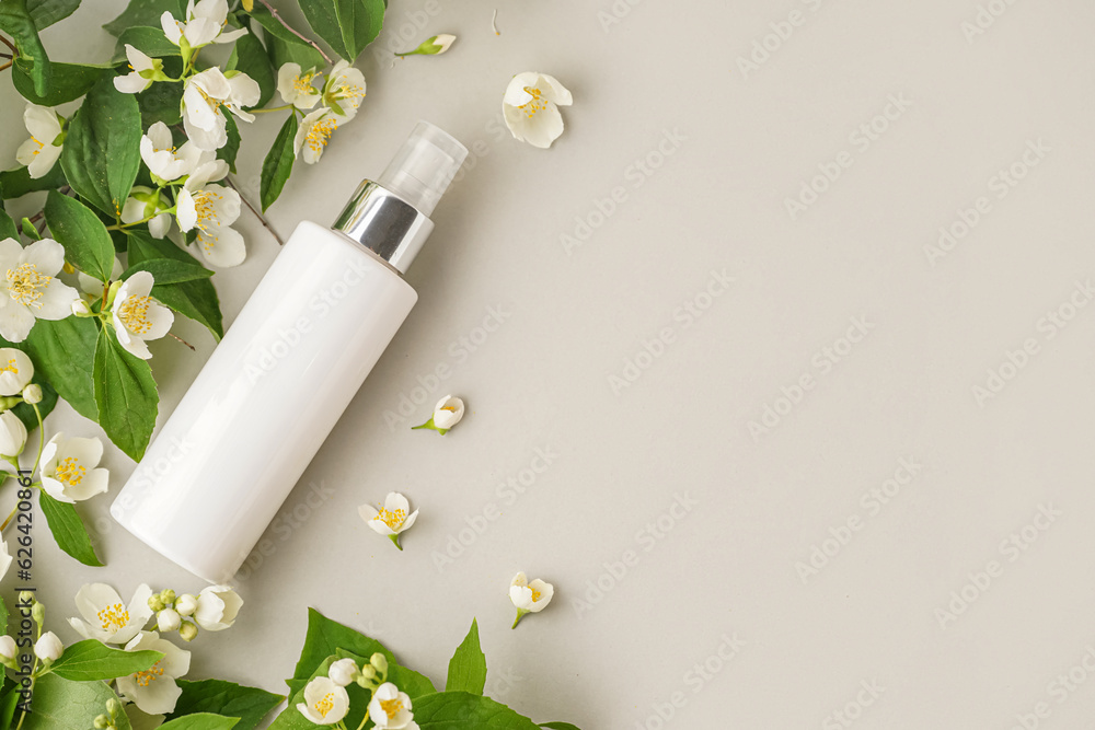 Composition with bottle of cosmetic product and beautiful jasmine flowers on light background