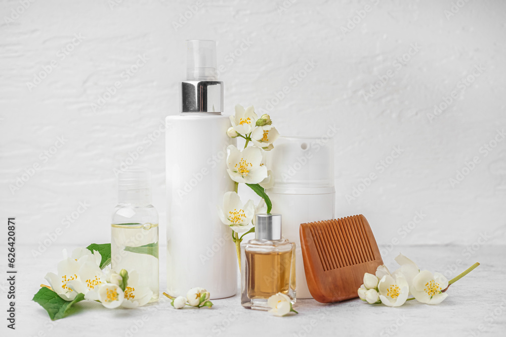 Set of cosmetic products, hair comb and beautiful jasmine flowers on light background