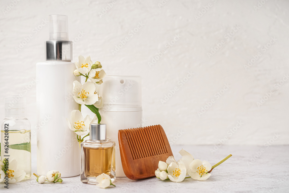 Set of cosmetic products, hair comb and beautiful jasmine flowers on light background