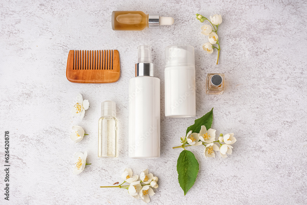 Composition with cosmetic products, hair comb and beautiful jasmine flowers on light background