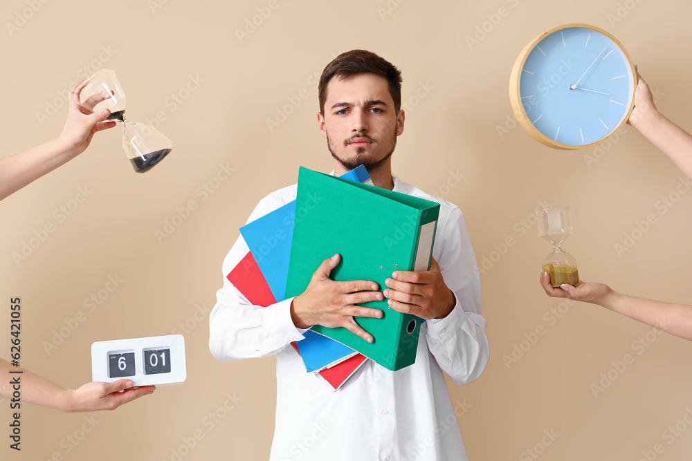 Stressed young man and hands with clocks on beige background. Deadline concept