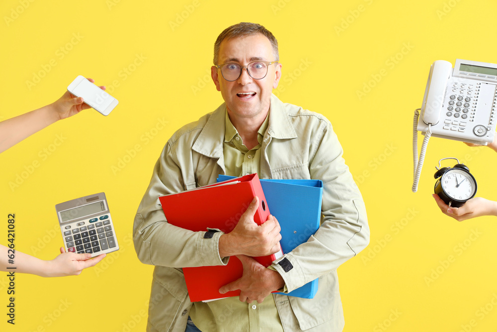 Stressed mature man and hands with things on yellow background. Deadline concept