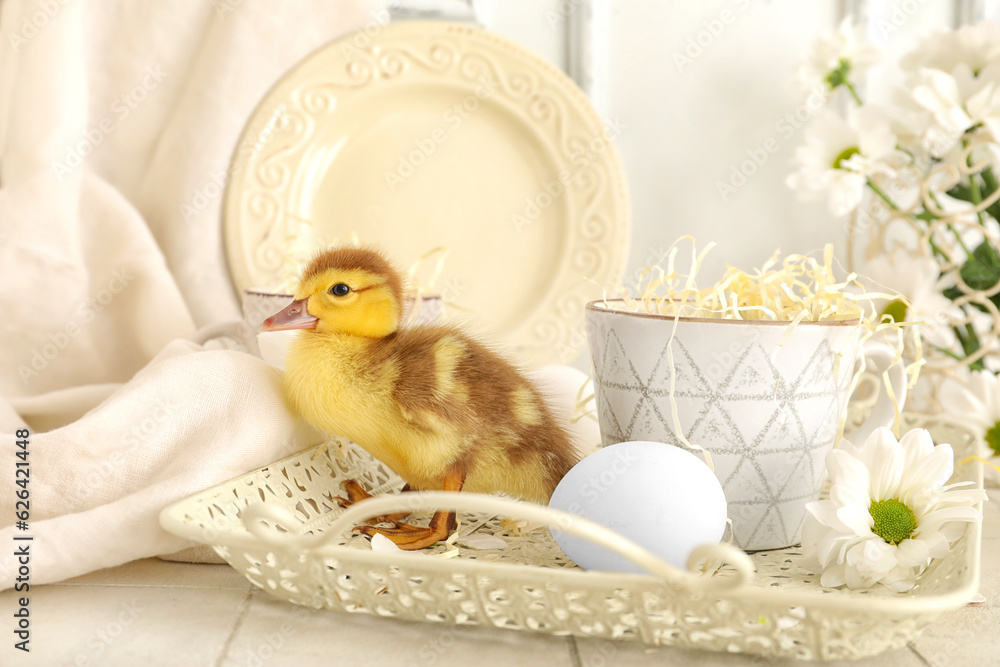 Cute duckling, tray with cup and chamomile flowers on white tile table