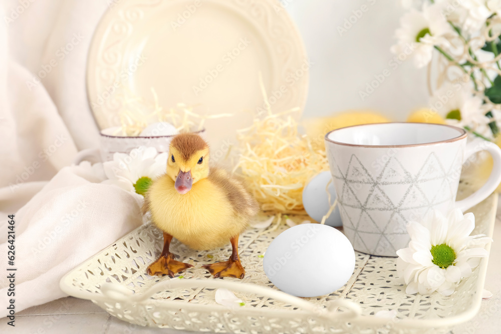 Cute duckling, tray with cup and chamomile flowers, closeup