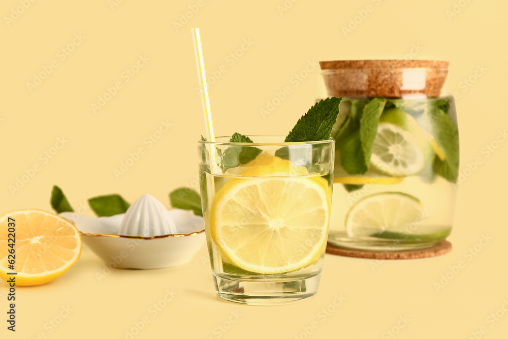 Glass of cold mojito and juicer on color background