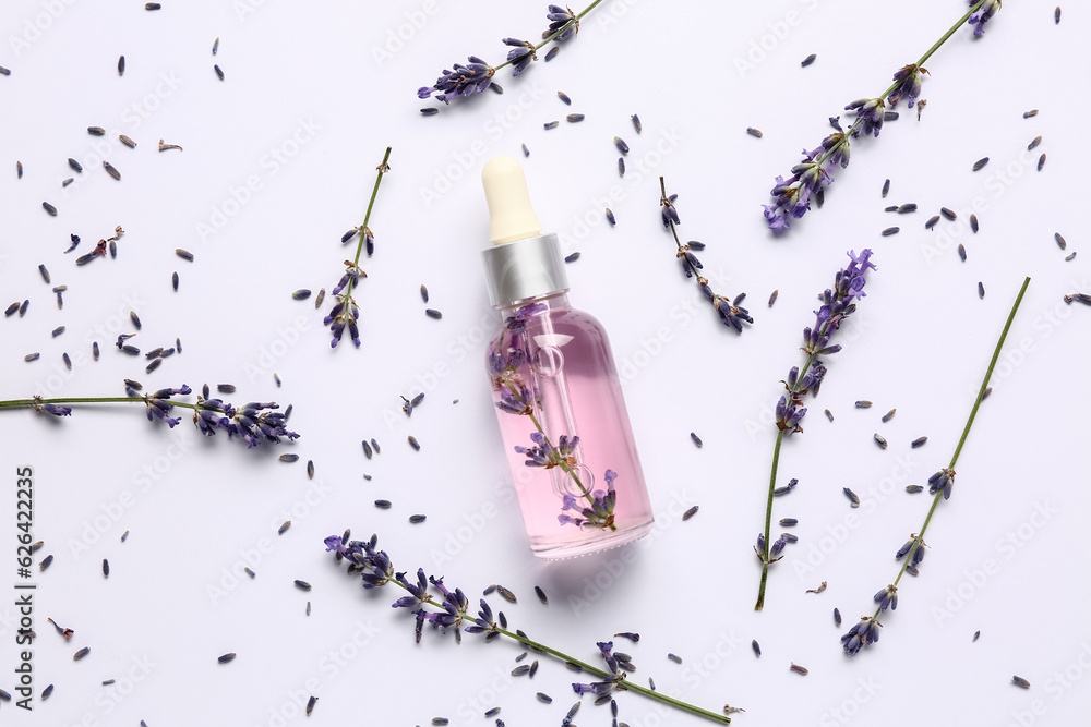 Composition with bottle of essential oil and lavender flowers on white background