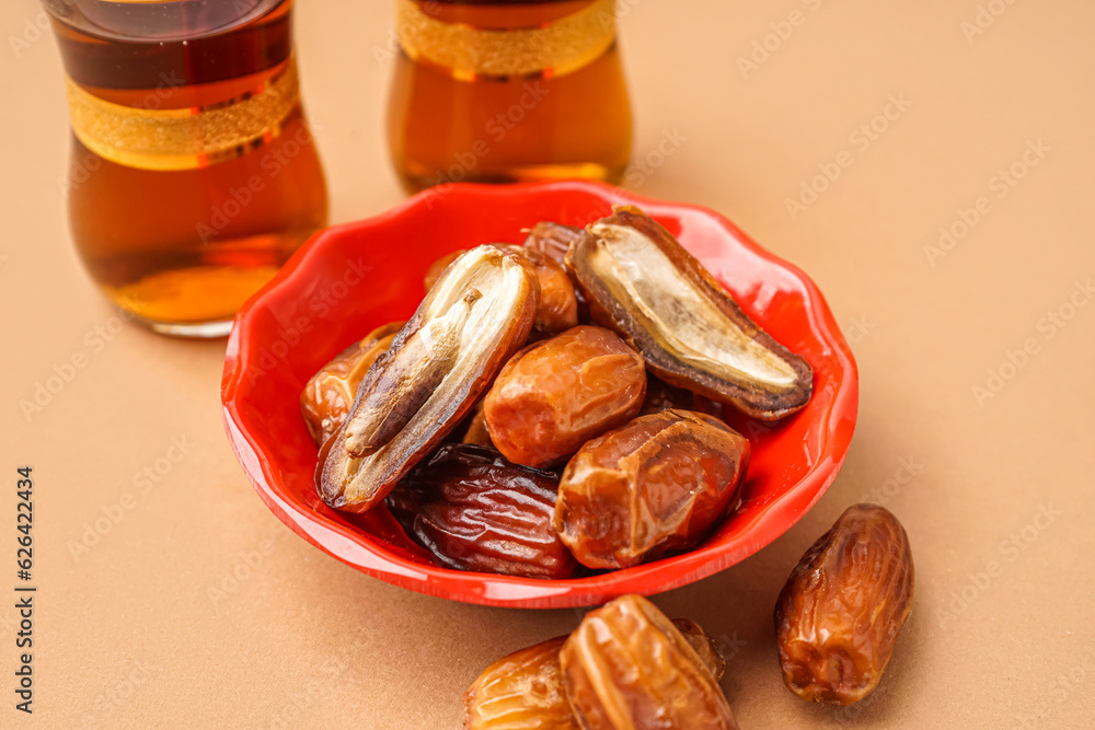 Bowl with dried dates on brown background