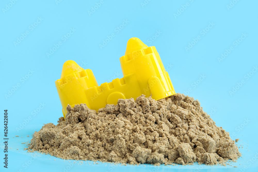 Castle made of sand with beach toy on blue background