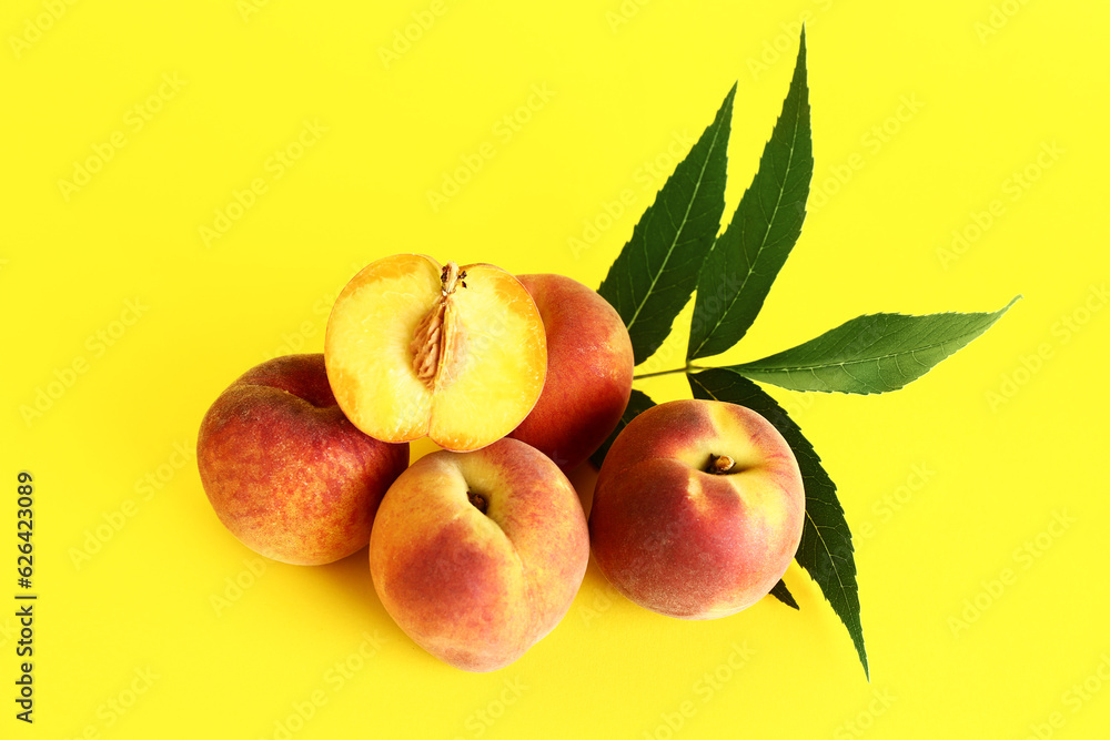 Sweet peaches and leaves on yellow background