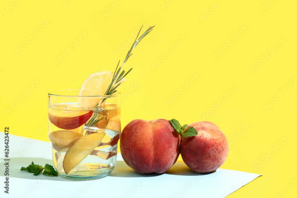 Glass of fresh peach lemonade with rosemary and mint on colorful background