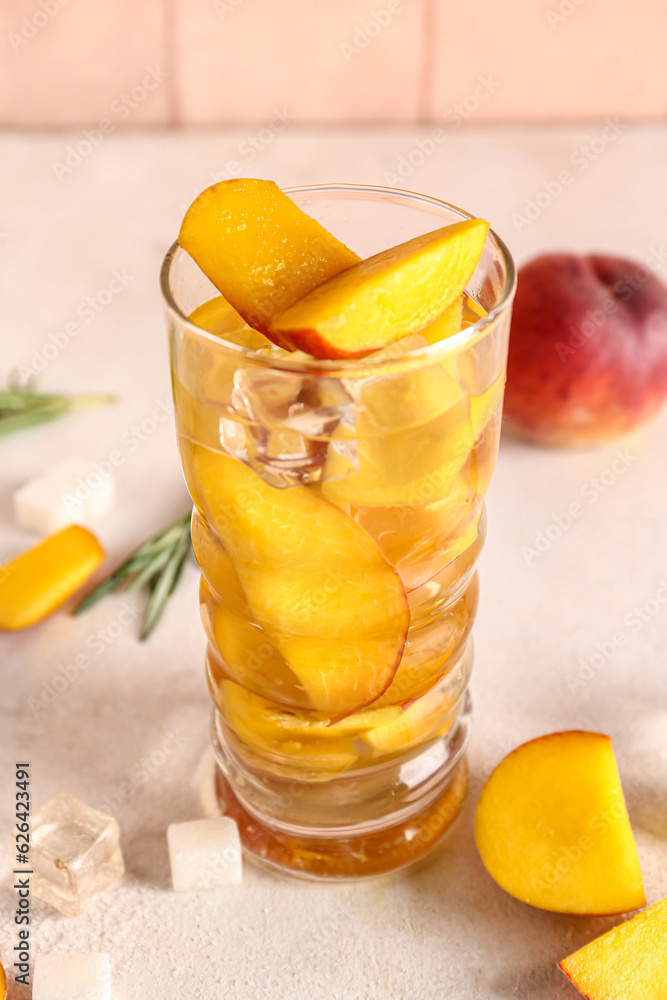 Glass of fresh peach lemonade on white table