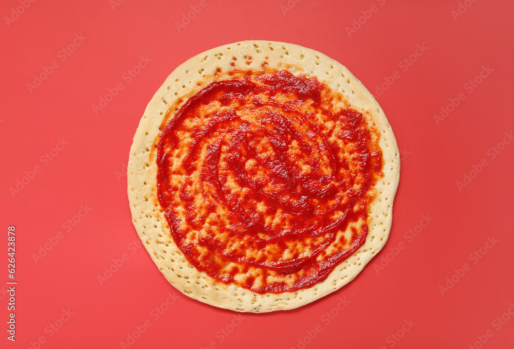 Pizza crust with tomato sauce on red background