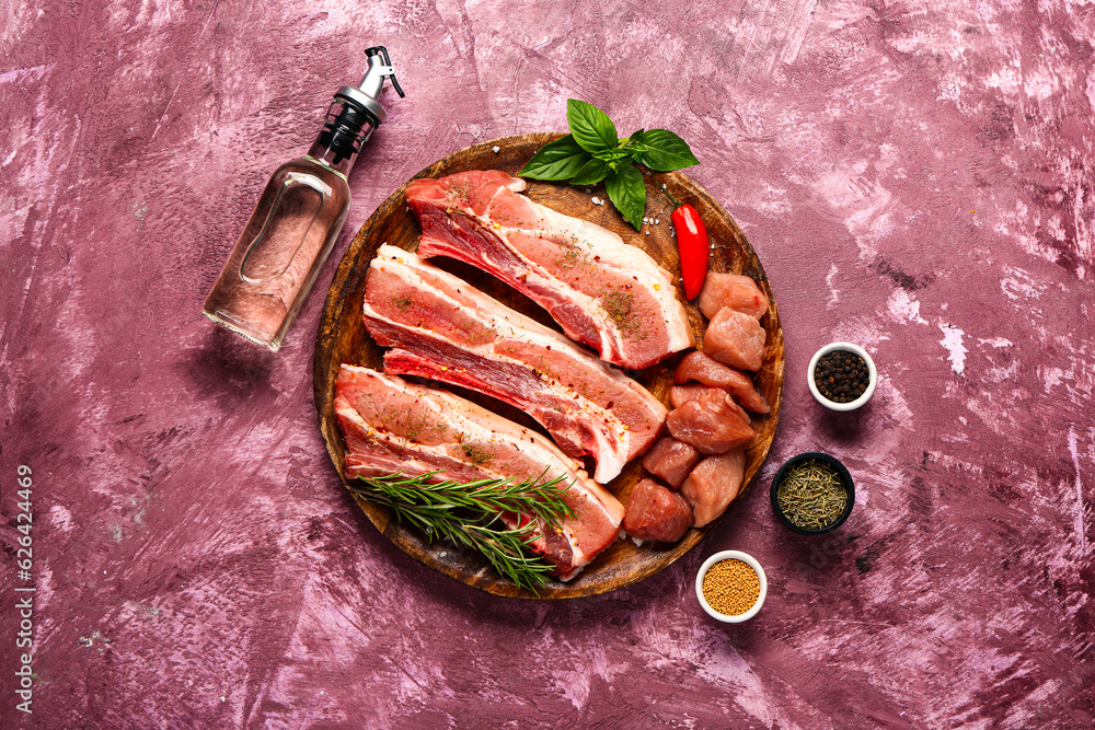 Plate with raw meat, oil and spices on color background