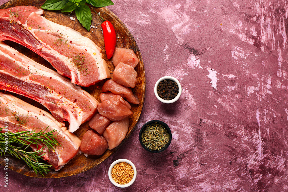 Plate with raw meat and spices on color background