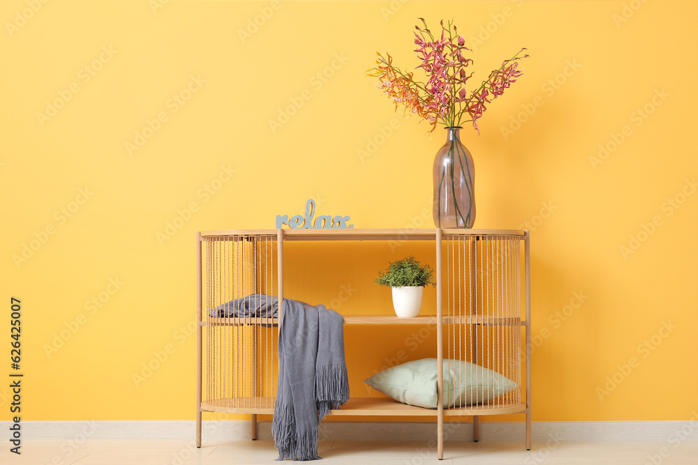 Shelving unit with cozy blanket near orange wall