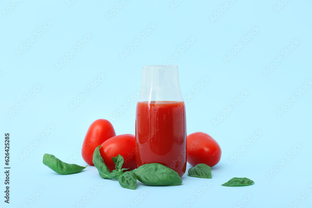 Bottle of tasty tomato juice on blue background