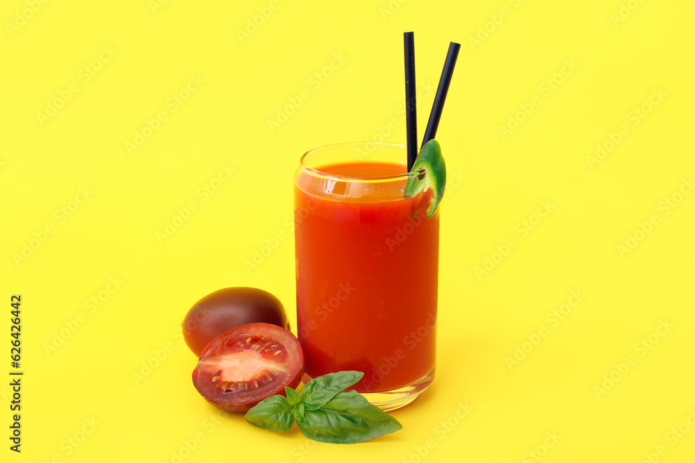 Glass of tasty tomato juice on yellow background